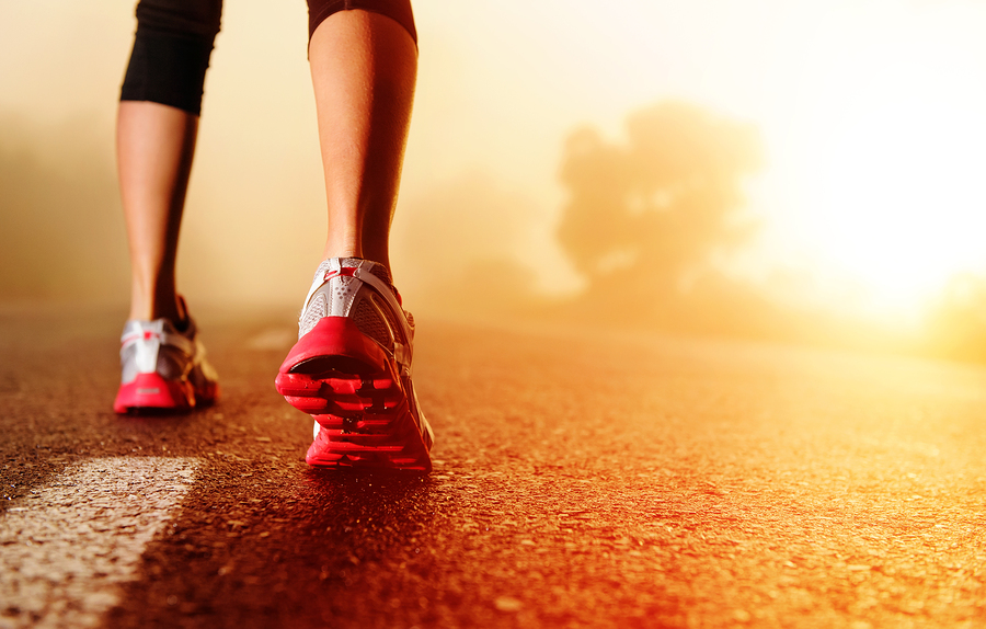 Athlete runner feet running on road closeup on shoe. woman fitness sunrise jog workout wellness concept.