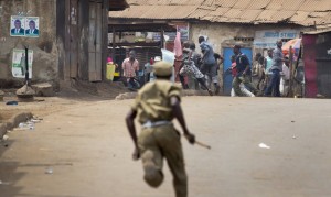 A policeman chases angry supporters of opposition leader Kizza Besigye, near to his party headquarters, in Kampala, Uganda Friday, Feb. 19, 2016. Police in Uganda arrested opposition leader Kizza Besigye at his party's headquarters Friday after heavily armed police surrounded the building and fired tear gas and stun grenades at his supporters who took to the streets. (AP Photo/Ben Curtis)