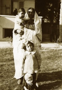 Kamran Afshar in the arms of his nanny, Naneh Sonbol Baji, and Haleh Afshar, standing behind a doll, in Tehran, 1940s. Sonbol Baji, who was of African extraction, was born in a harem and freed in childhood from the court of the last Qajar king, Ahmad Shah (1898-1930). She moved to the home of her future host family, the Afshars, where she grew up, married, and raised her son. She remained there until the end of her life. Photograph: Courtesy of Kamran Afshar 