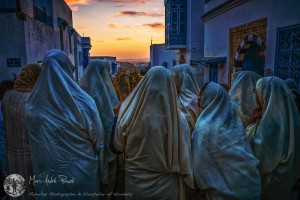 A group of women dressed in traditional Tunisian veil, the safsari in anticipation of a wedding. The bride is covered with a golden veil (center) and the group is walking in streets, singing and making the Berber cry. photo: marcpause.photoshelter.com