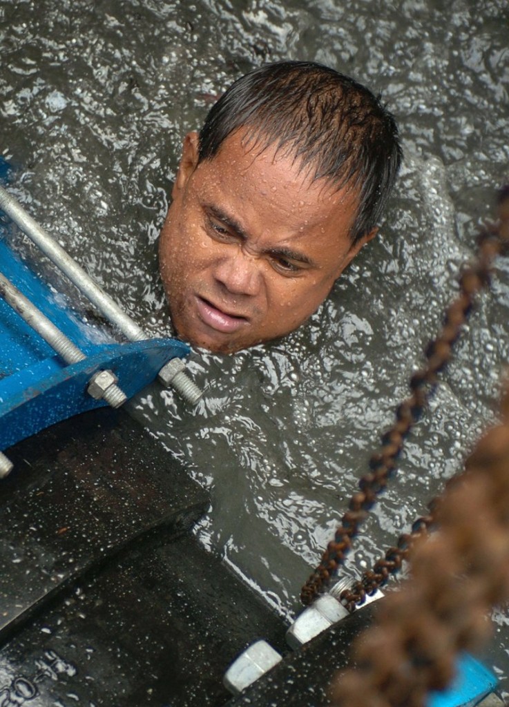 5 November 2004: A worker from the Maynilad Water utilities struggles to install a valve underwater on an excavated Manila's main water line as part of an upgrade of the water distribution systemRomeo Gacad/ AFP
