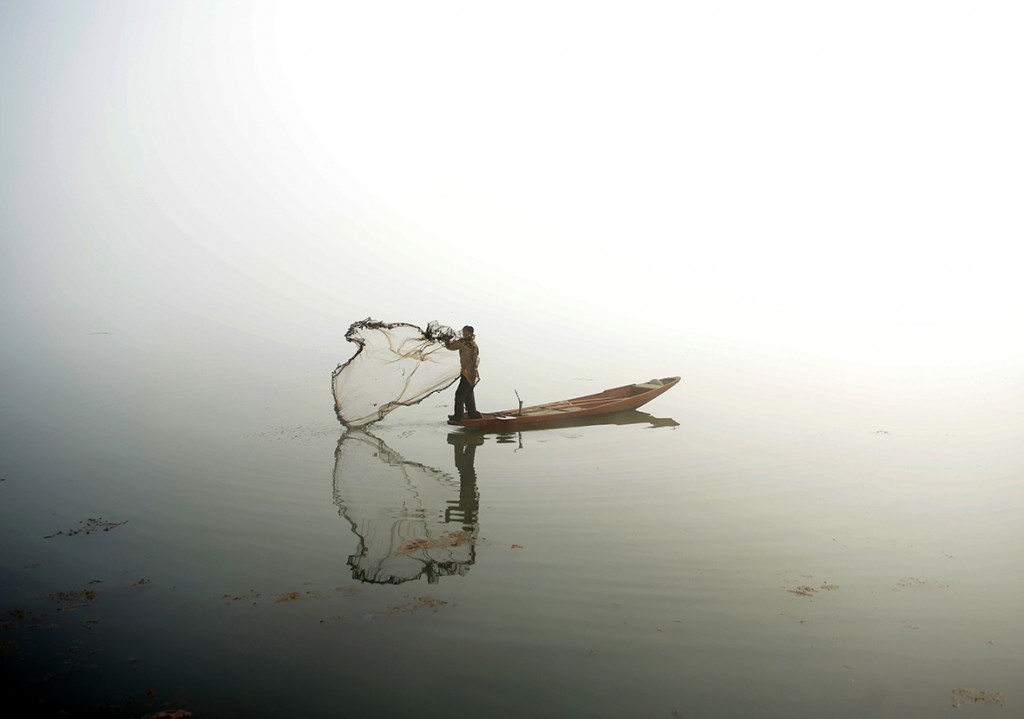 13 January, 2016: A Kashmiri fisherman throws out his net from his boat on Dal lake during dense fog in SrinagarTauseef Mustafa/ AFP