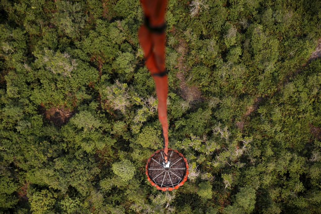 10 September 2015: A helicopter carries water to be dropped on a burning forest at Ogan Komering Ulu area in Indonesia's south Sumatra province (Beawiharta/ Reuters)