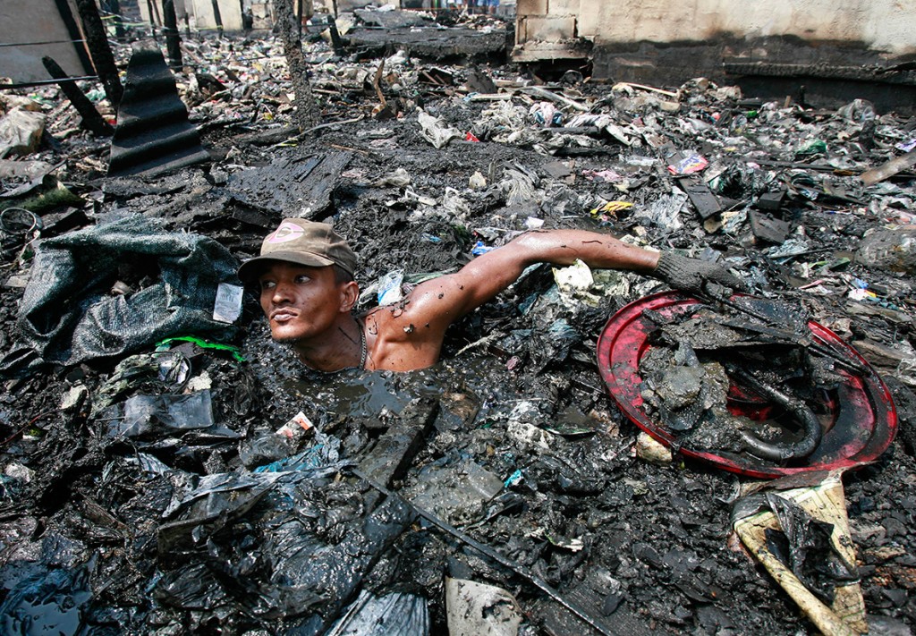 13 April 2007: A man searches through debris in polluted water looking for items to salvage after a fire in a slum in Malabon, north of ManilaDarren Whiteside/ Reuters