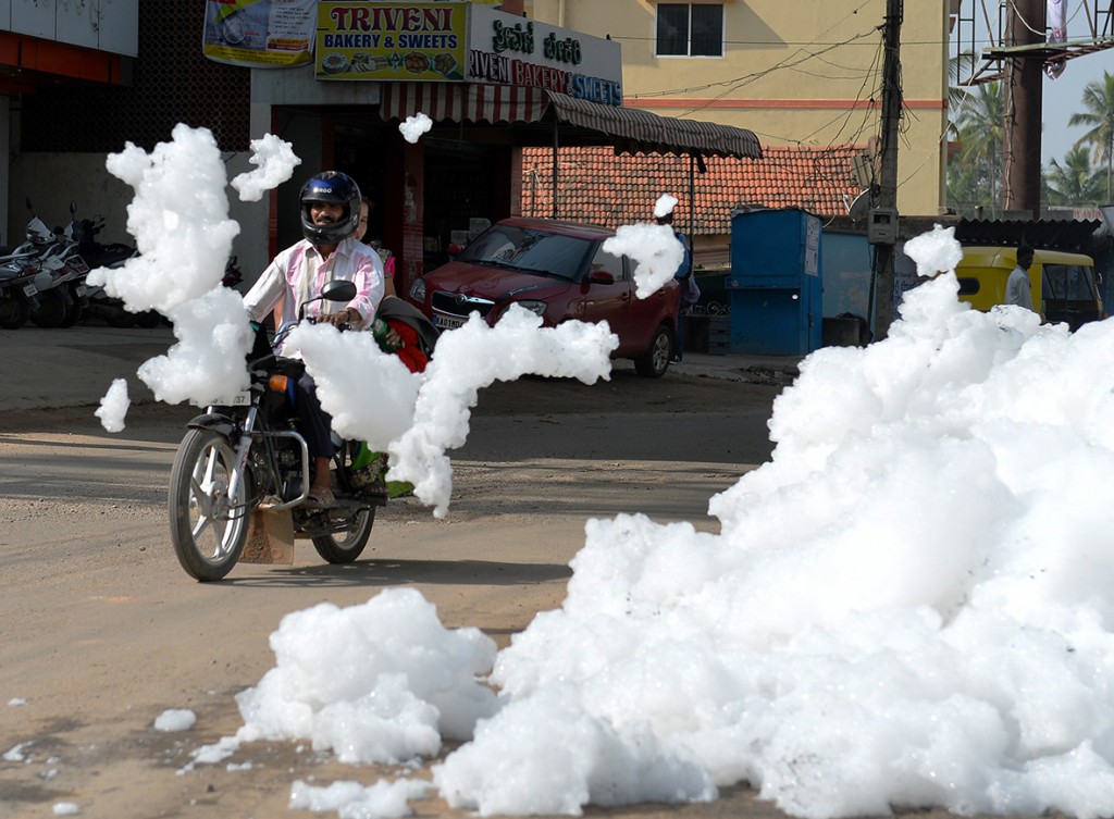 1 May 2015: A motorcyclist negotiates away from piles of foam at Varthur Kodi junction situated in east Bangalore. The innocuous-looking foam is toxic effluent caused by the polluted sewage water overflowing from nearby Varthur LakeManjunath Kiran/ AFP