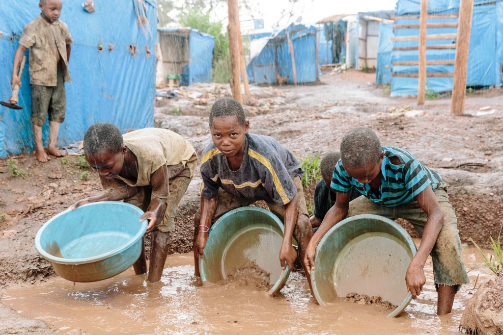 Using makeshift pans, children sluice gold ore while standing ankle deep in water. Photograph: Eelco Roos/Hivos
