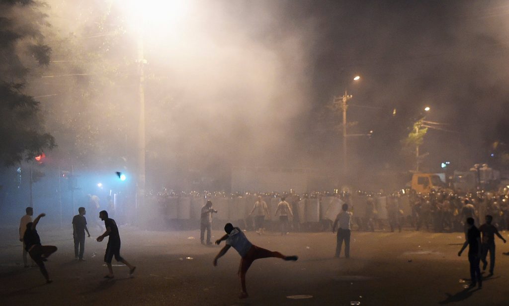 Demonstrators who had gathered in show of support for gunmen holding several hostages in police station, clash with riot police in Yerevan. Photograph: Reuters