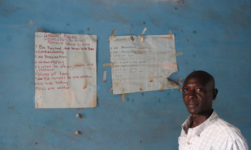 Mohamed Moray, clinical supervisor for Caps, poses before group counseling guidelines adorning the walls of the organisation’s office in Kailahun. Photograph: Ryan Brown