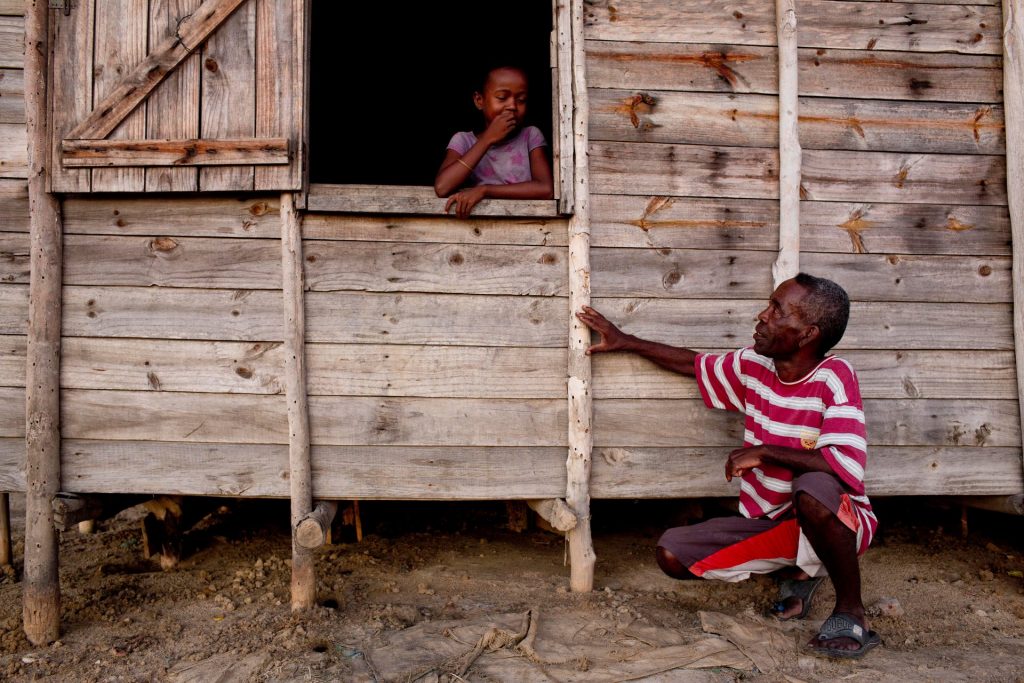 François, who has lived in Tanambao village, Madagascar, all his life, shows his daughter a mark on his house that indicates the water level during last year’s floods.