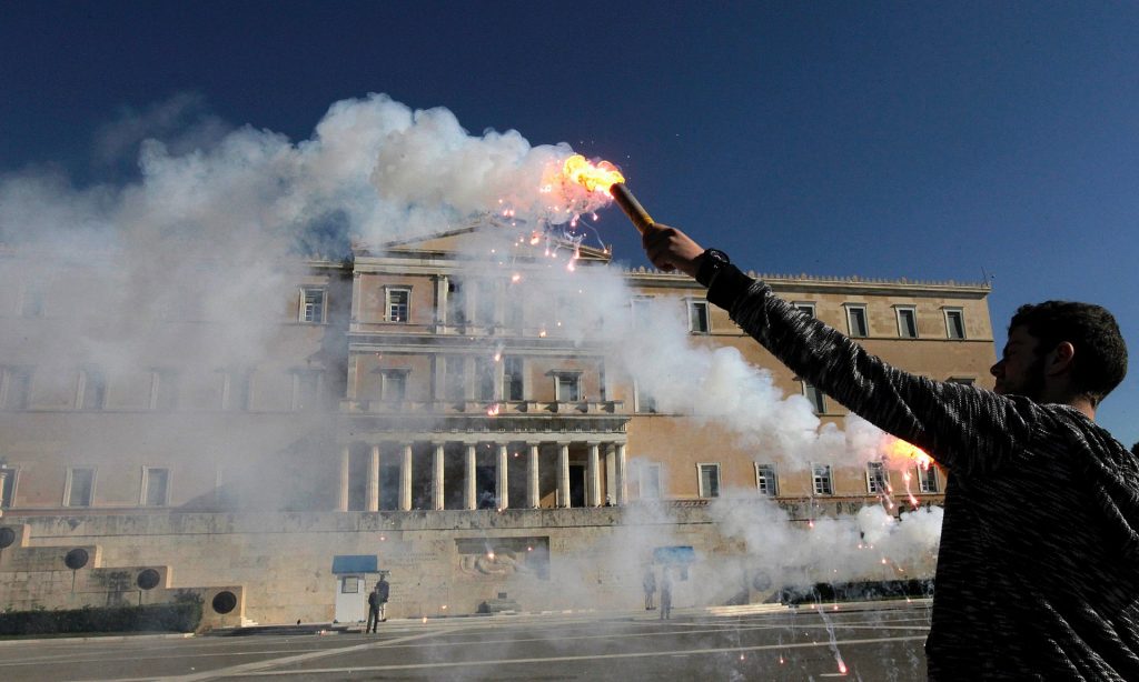 A student holds a flare in front of the Greek parliament building during an anti-austerity protest in Athens last November. The UK, Greece and Portugal were the only three OECD countries that saw real wages fall between 2007 and 2015. Photograph: EPA