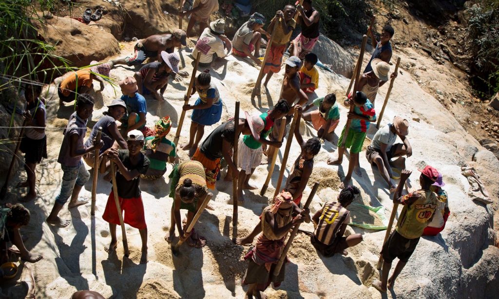Women and children pound stones to find gold ore in Madagascar, April 2016. Photograph: Kate Holt 