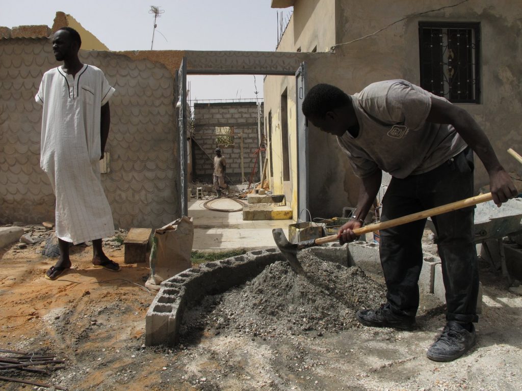Vieux Fall, left, stands in the family compound in Nouakchott, Mauritania, as builders work. Photograph: Alex Duval Smith