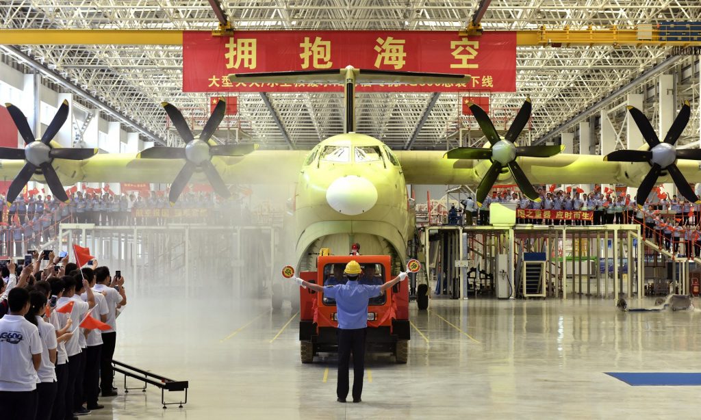 Chinese workers wave national flags as the Amphibious aircraft AG600 is rolled off a production line in Zhuhai in south China’s Guangdong Province. Photograph: Liang Xu/AP