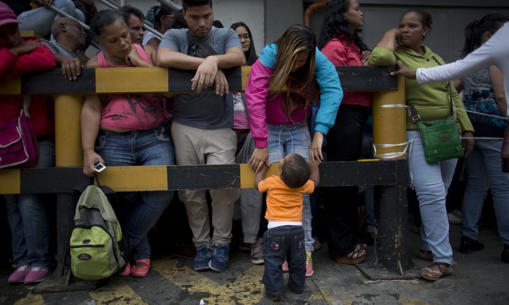 A mother and son wait to buy food outside a supermarket in Caracas, Venezuela. Photograph: Ariana Cubillos/AP