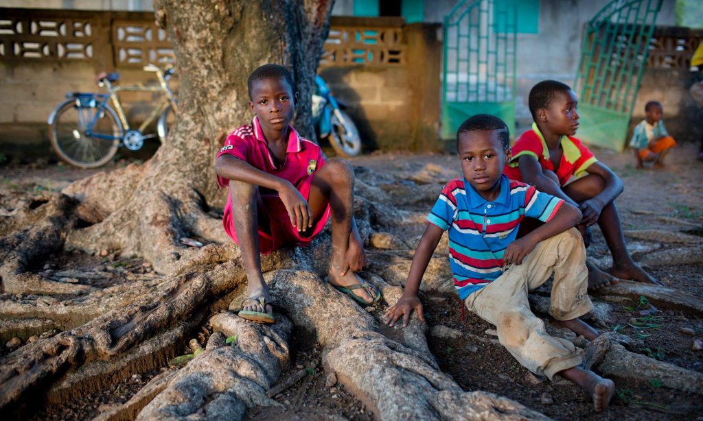 Children sit outside a clinic in a community near Doko, Siguiri, in northern Guinea. They have just been vaccinated for polio as part of a Unicef campaign backed by the Spanish government. Photograph: Kate Holt/Unicef
