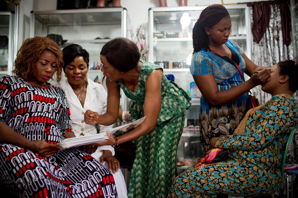 An apprentice hairdresser at the Jumelle salon in Conakry shows a client different family planning methods. Photograph: Kate Holt