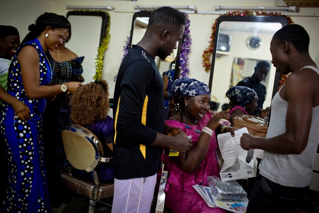Young men who have come to Miskaa Salon for cut price condoms are shown how to use them correctly by apprentice hairdresser Nene Diakité. Photograph: Kate Holt