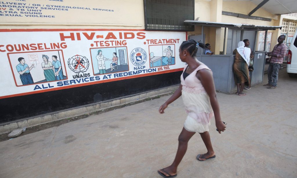 A woman walks past Aids information on the wall of the Redemption hospital in New Kru Town near Monrovia, Liberia. Photograph: Ahmed Jallanzo/EPA