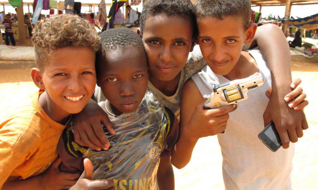  Boys pose with a toy gun at the marketplace in Mbera refugee camp.