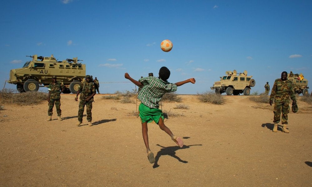 Ugandan soldiers deployed with Amisom play football with Somali children after taking back a town from al-Shabaab. Photograph: Irin