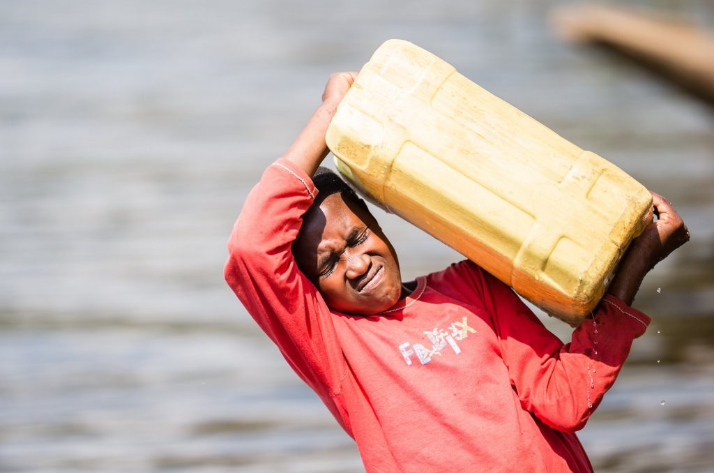 Doreen lifts the full jerry can. Getting the 20kg load into position can be a struggle, but once she has it balanced on her head, her neck is strong enough to carry the weight efficiently on the long walk home.