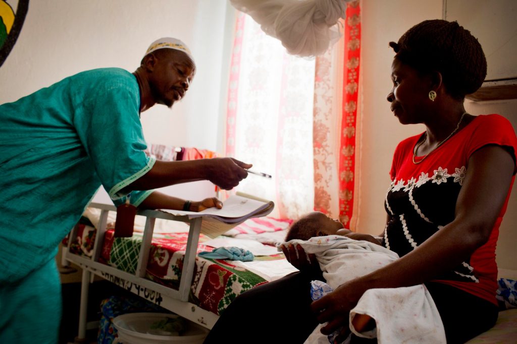 Edwin Yarkopwalo (left) takes down details about a baby in order to register its birth at the Kakata Rennie hospital.