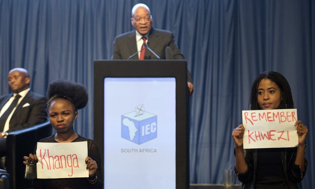 Protesters hold up placards during Jacob Zuma’s speech at the announcement of the results of South Africa’s municipal elections . Photograph: Herman Verwey/AP