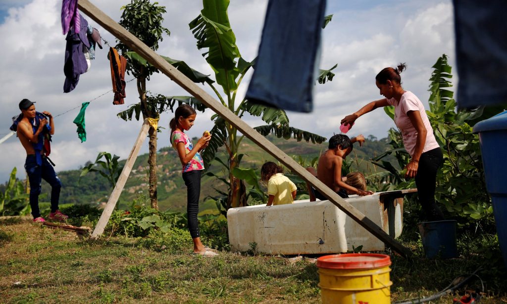 Lisibeht Martinez, right, 30, who was sterilized a year ago, plays with her children in a bathtub in the backyard of their house in Los Teques. Photograph: Carlos Garcia Rawlins/Reuters