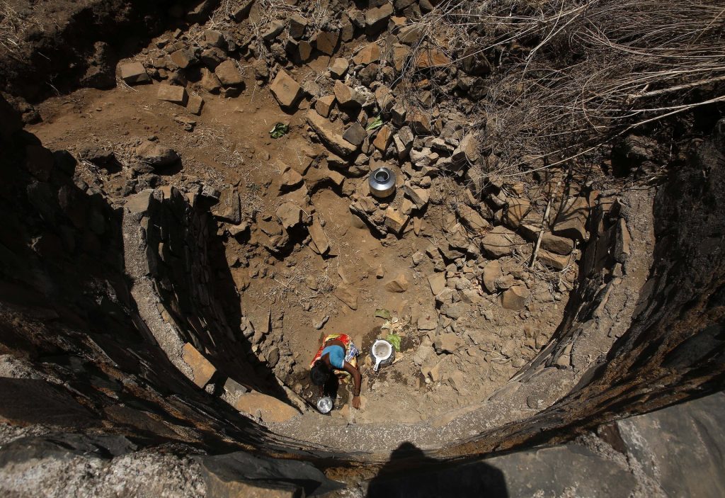 An Indian woman tries to collect water from a dried-up well in Maharashtra state. Across India, 76 million people lack access to safe water. Photograph: Rajanish Kakade/AP