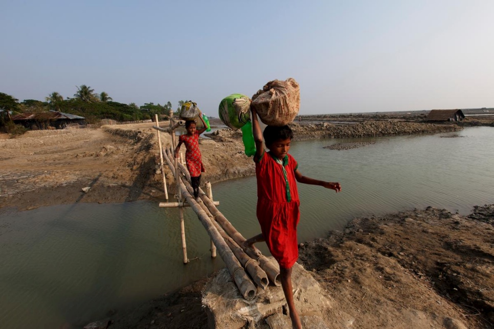Girls cross a bamboo bridge on Katubidia island in Bangladesh, a nation where millions of people are at risk due to rising sea levels. © UNHCR/Saiful Huq Omi