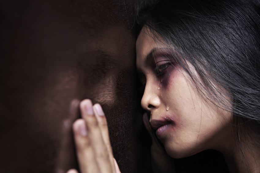 Injured woman leaning sadly on wooden wall, concept for domestic violence