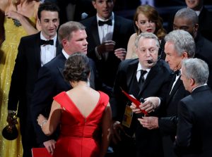 Brian Cullinan (L) and Martha Ruiz of PricewaterhouseCoopers look on as presenter Warren Beatty holds the card for the Best Picture Oscar awarded to "Moonlight," after announcing by mistake that "La La Land" was the winner. REUTERS/Lucy Nicholson
