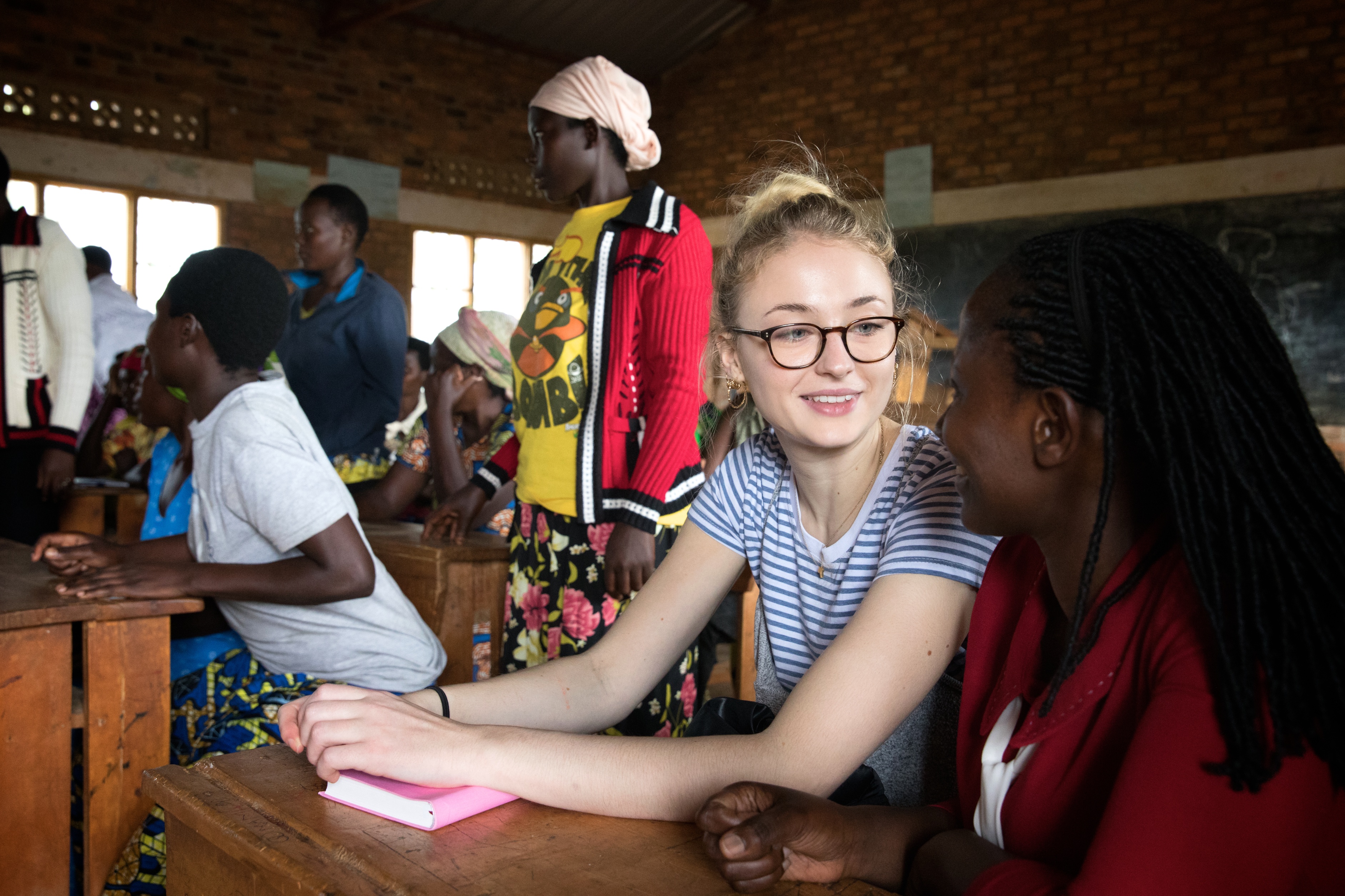 How 'Game of Thrones' Star Sophie Turner's Activism Was Inspired by her Role as Sansa Stark © Hazel Thompson for WFWI UK Sophie Turner visiting WFWI projects in Rwanda. Caption: Justine Mbabazi, Social Empowerment Manager for Women for Women International  Rwanda, explaining the content of the class to Sophie Turner. The class is taking place in a local primary school in Mubano village (Masaka Sector), central Rwanda. During the year-long programme, women come together in classes of 25 to learn a marketable job skill (such as tailoring, brick-making or poultry-keeping) as well as business training to turn their chosen skill into a stable income. They also learn practical knowledge about health, nutrition and about their rights on key issues like voting, access to land and domestic abuse.