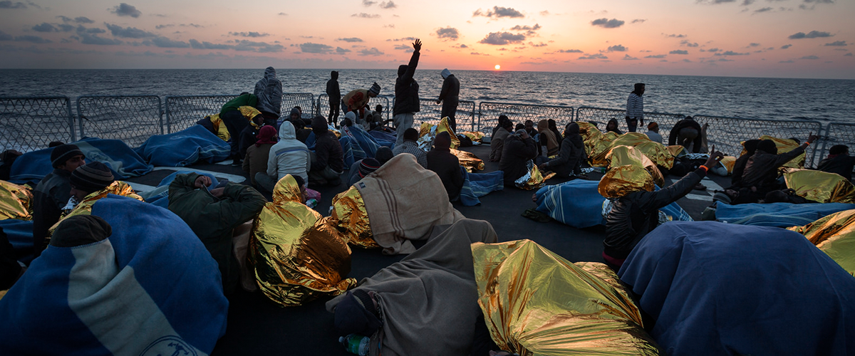 A group of rescued people on the deck of an Italian naval vessel as the sun sets in the Mediterranean. ©UNHCR/A. D'Amato