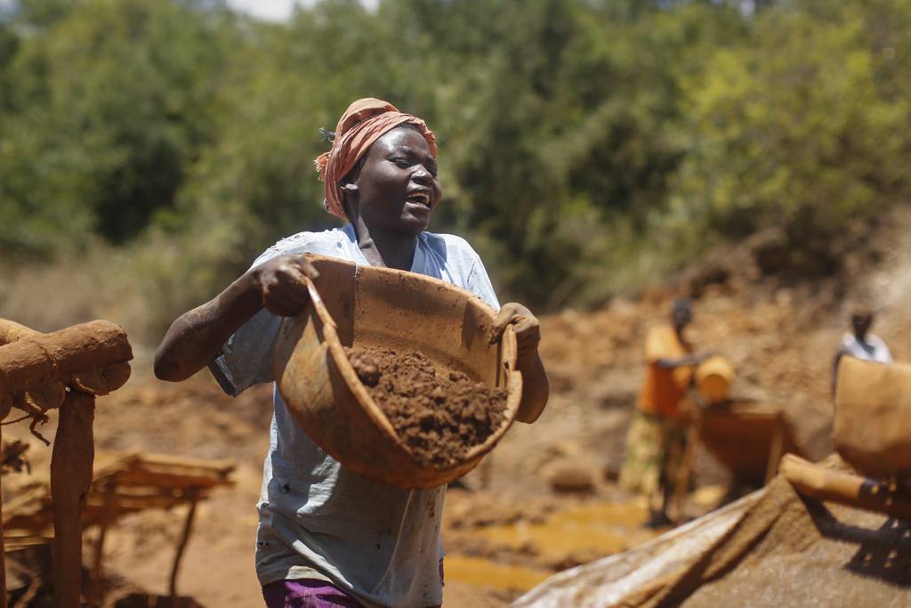 A woman carries a basin full of ore to be washed at one of the gold mining sites in Macalder, Migori county, western Kenya, 29 February 2016.