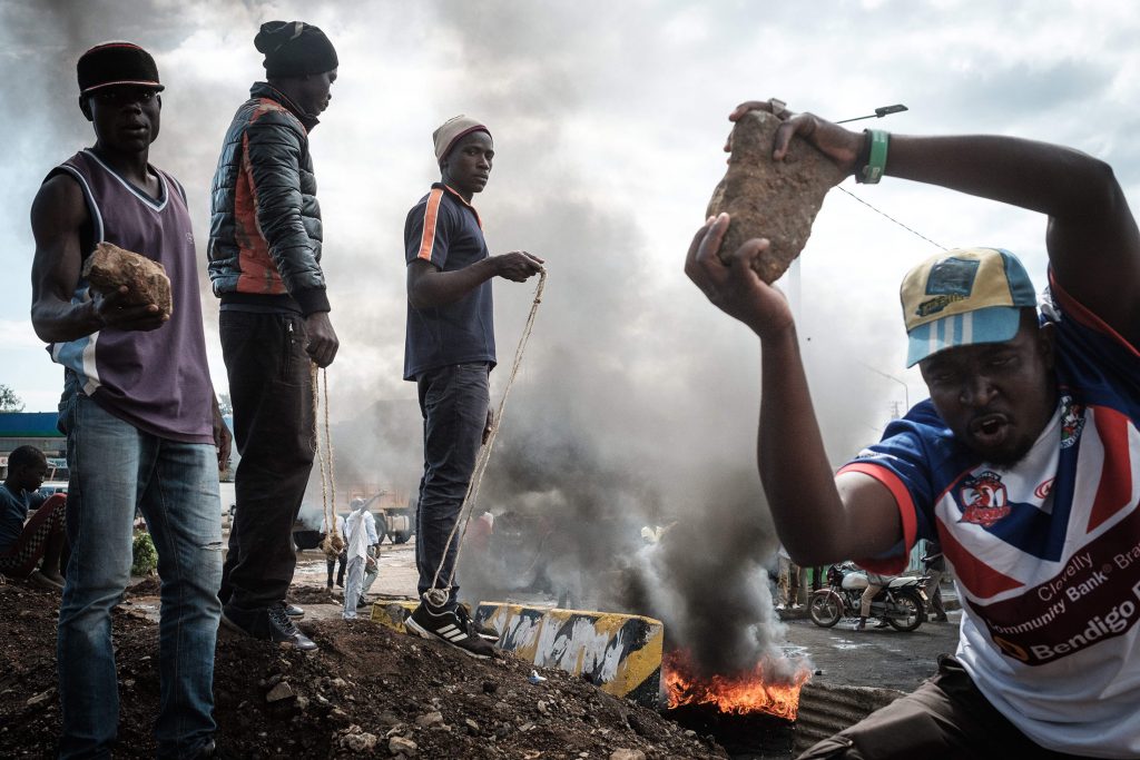 Opposition supporters hold up bricks as they block streets and burn tires during a protest in Kisumu, Kenya, on October 11, 2017. Supporters of Kenya's opposition leader Raila Odinga took to the streets as poll officials mull their next move after his withdrawal from a presidential election plunged the country into uncharted waters. / AFP PHOTO / YASUYOSHI CHIBA        (Photo credit should read YASUYOSHI CHIBA/AFP/Getty Images)