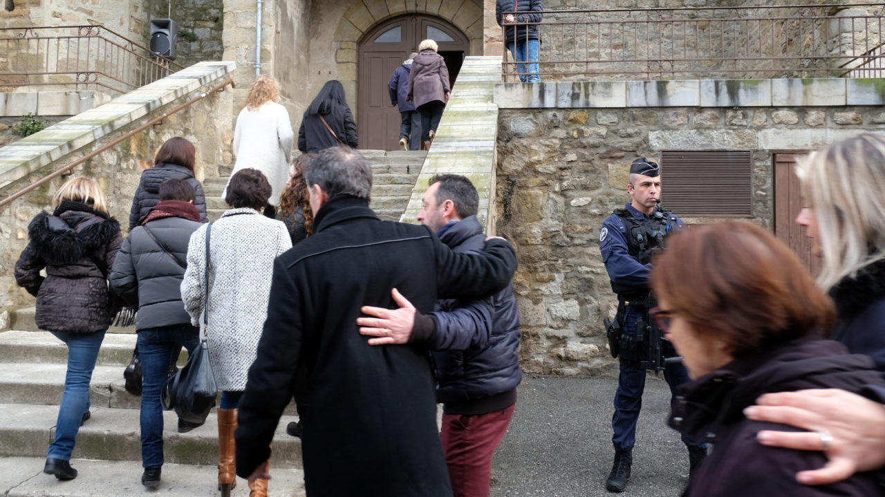 Mourners arrive at the Saint Etienne Church in Trebes in southwest France for a service of remembrance on March 25, 2018, two days after a man carried out an attack in which four people were killed. Mourners in this rural French town rocked by a deadly Islamist attack held a mass on Palm Sunday to pay tribute to the victims, including a policeman hailed a hero for offering himself in place of a hostage. Lieutenant-Colonel Arnaud Beltrame, 44, was shot and stabbed after taking the place of a woman whom Radouane Lakdim had been using as a human shield during his attack Friday on a supermarket in the small town of Trebes. / AFP PHOTO / Eric CABANIS