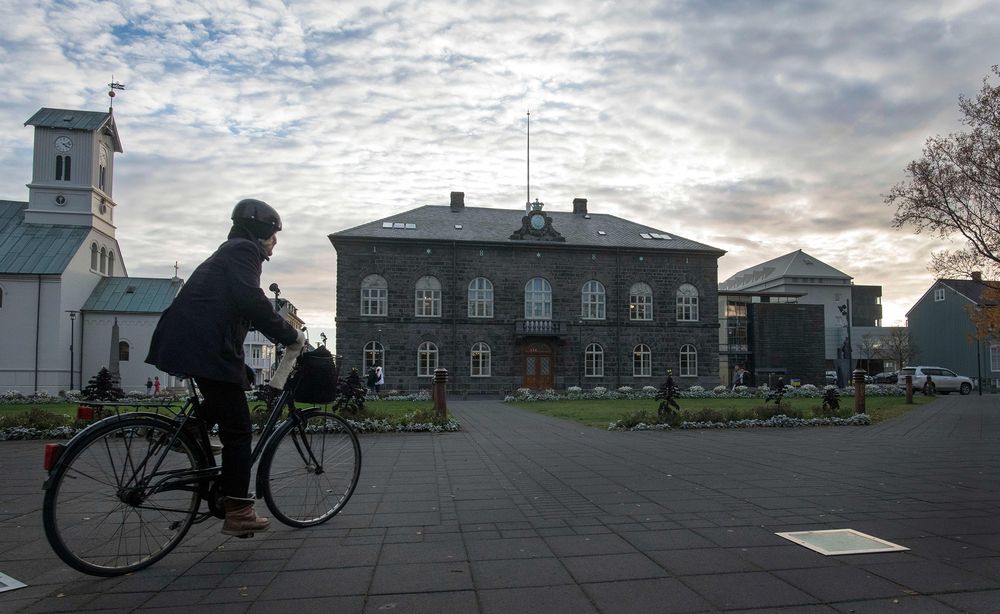 A woman cycles past the Althingi Parliament building in Reykjavik. Photographer: Halldor Kolbeins/AFP via Getty Images