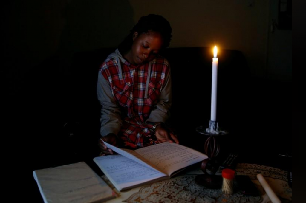Student Rutendo Madziva reads by candlelight during an electrical power cut in Marondera, Zimbabwe, May 14, 2019. REUTERS/Philimon Bulawayo