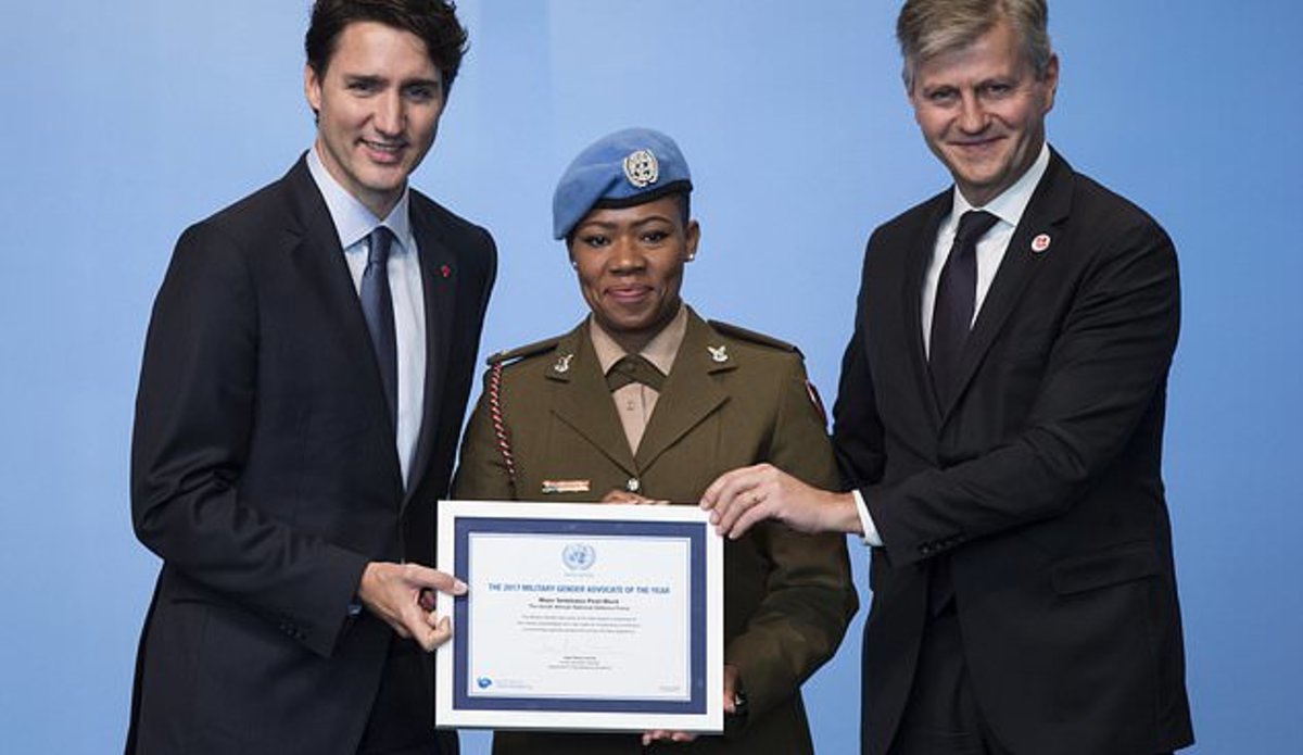 Prime Minister Justin Trudeau, left, and United Nations Under-Secretary-General for Peacekeeping Operations Jean-Pierre Lacroix, right, present the 2017 UN Military Gender Advocate of the Year award to Major Seitebatso Pearl Block, of The South African National Defence Force, during the 2017 United Nations Peacekeeping Defense Ministerial conference in Vancouver, British Columbia, Canada, on Wednesday Nov. 15, 2017.  (Darryl Dyck/The Canadian Press via AP)