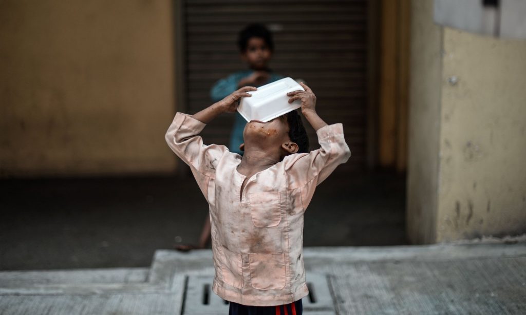 A homeless child eats food on a street in Kuala Lumpur. A report by Oxfam and the Institute for Development has identified a global trend towards fast food. Photograph: Mohd Rasfan/AFP/Getty Images