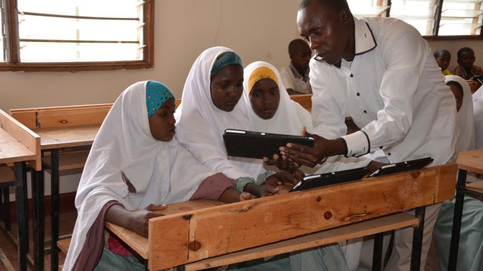 Michael Mutinda, a teacher in one of the primary schools at Dadaab refugee camp in Kenya, shows his pupils how a tablet computer works, in this 2014 file photo. © UNHCR/ D.Mwancha