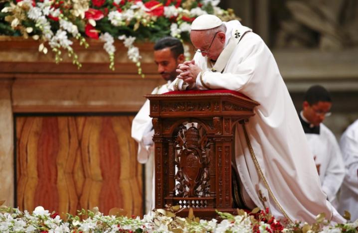 Pope Francis kneels as he leads the Christmas night Mass in Saint Peter's Basilica at the Vatican December 24, 2016. REUTERS/Tony Gentile