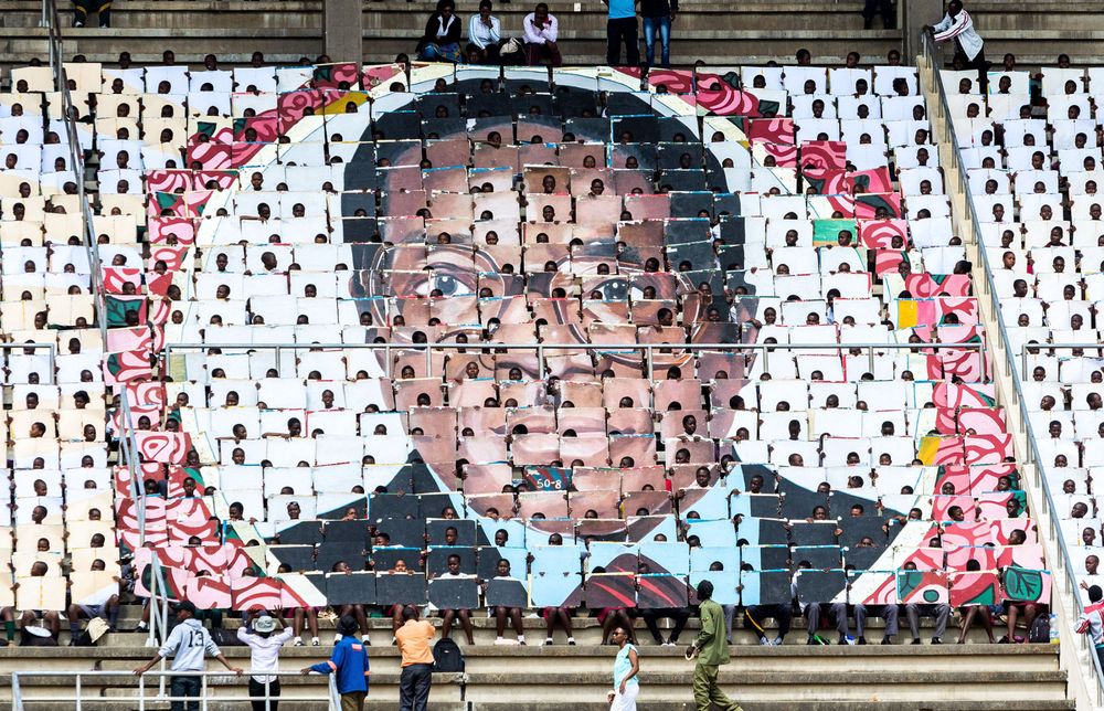 School children hold an image of Zimbabwe’s President Robert Mugabe during the country’s 37th Independence Day celebrations. Photographer: Jekesai Njikizana/AFP via Getty Images