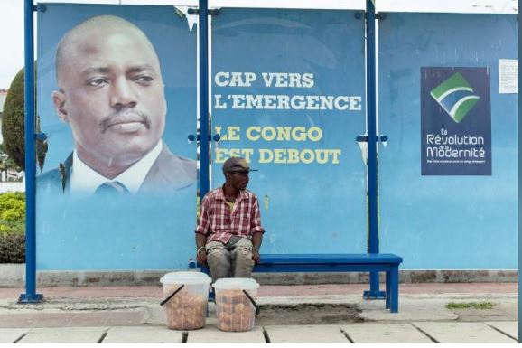 A vendor sits at a bus stand with pictures of President Joseph Kabila in Kinshasa, Democratic Republic of Congo December 31, 2016. REUTERS/Robert Carrubba