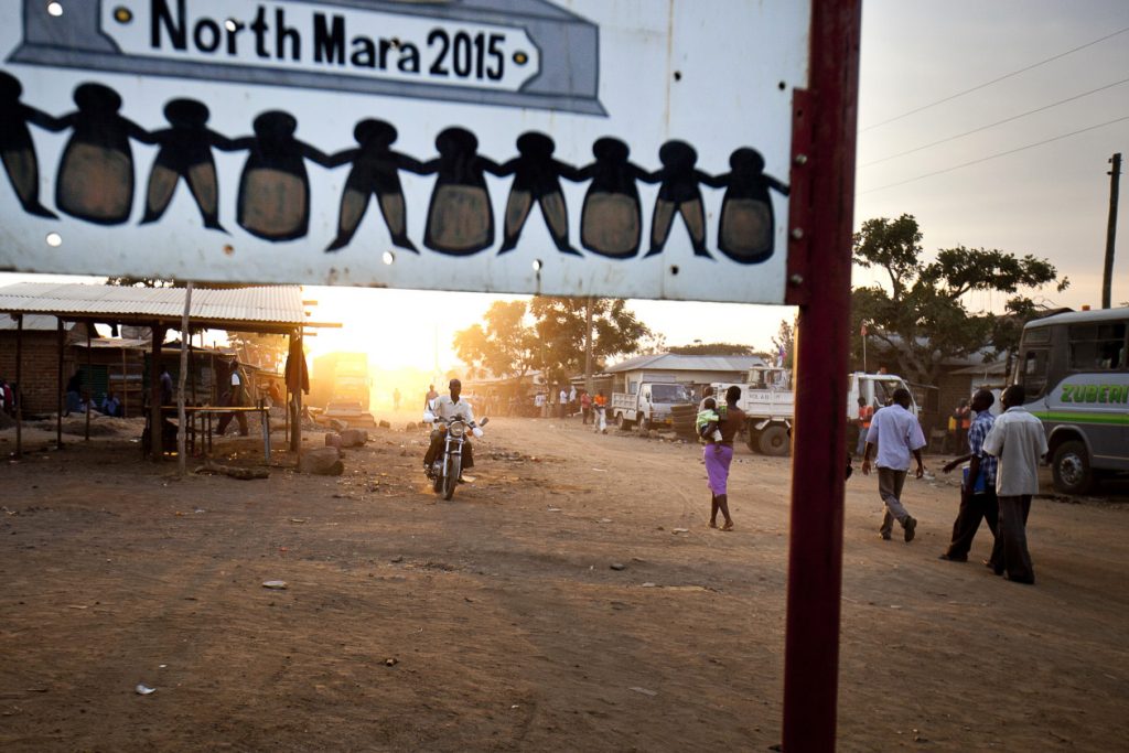 A motorcycle and pedestrians pass along a dirt road in the district of Nyangoto, Tanzania. Photographer: Trevor Snapp